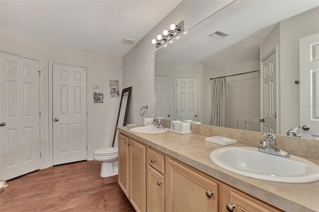 bathroom with oversized vanity, toilet, dual sinks, and hardwood / wood-style flooring