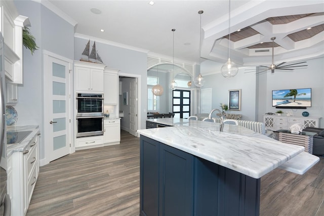 kitchen featuring white cabinetry, ceiling fan, a kitchen island with sink, decorative light fixtures, and dark hardwood / wood-style flooring