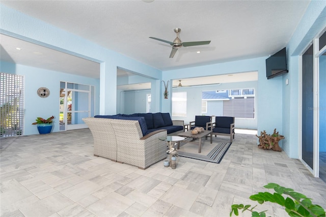 living room featuring ceiling fan and a textured ceiling