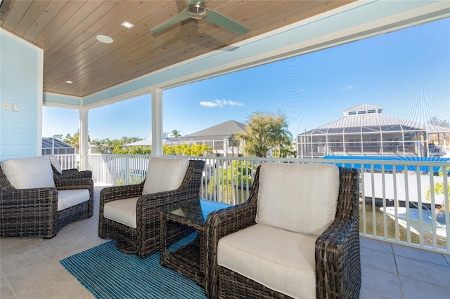 view of patio featuring ceiling fan and glass enclosure