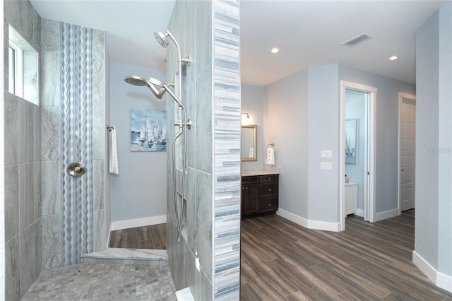 bathroom featuring vanity, hardwood / wood-style floors, and a tile shower