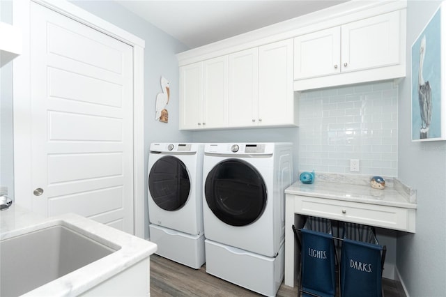 clothes washing area featuring cabinets, dark hardwood / wood-style floors, sink, and washing machine and clothes dryer