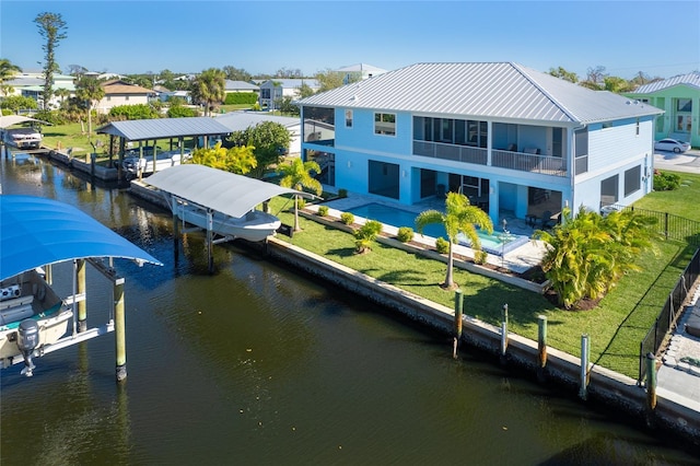 back of property featuring a balcony, a lawn, a water view, and a patio