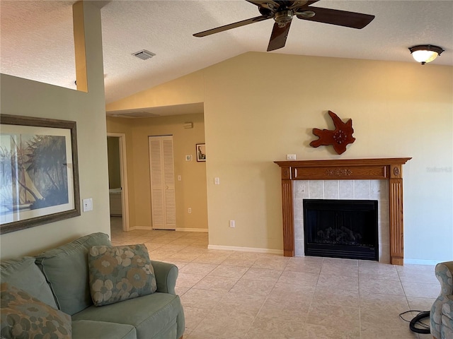 tiled living room with vaulted ceiling, a textured ceiling, ceiling fan, and a tile fireplace