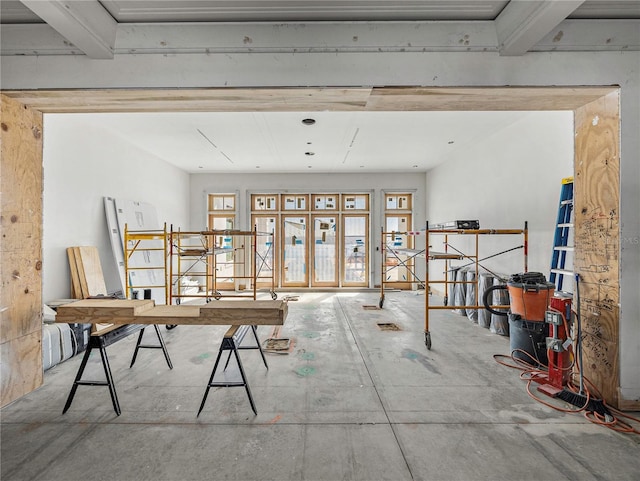 miscellaneous room featuring plenty of natural light, beam ceiling, and concrete flooring