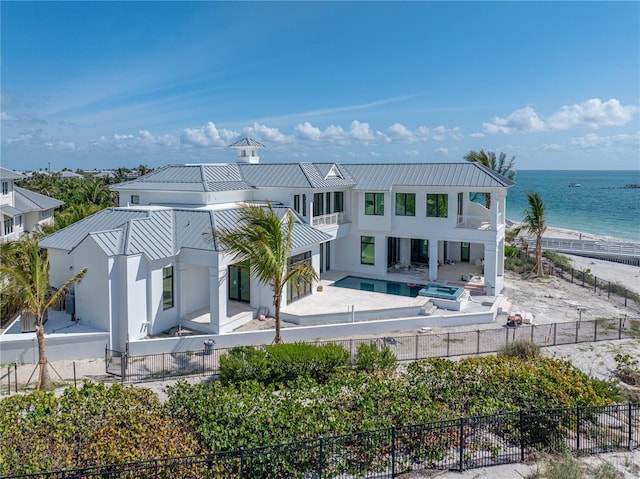 894 Hill Tide Ln, Boca Grande, FL 33921 - back of property featuring a fenced backyard, metal roof, stucco siding, a patio area, and a water view