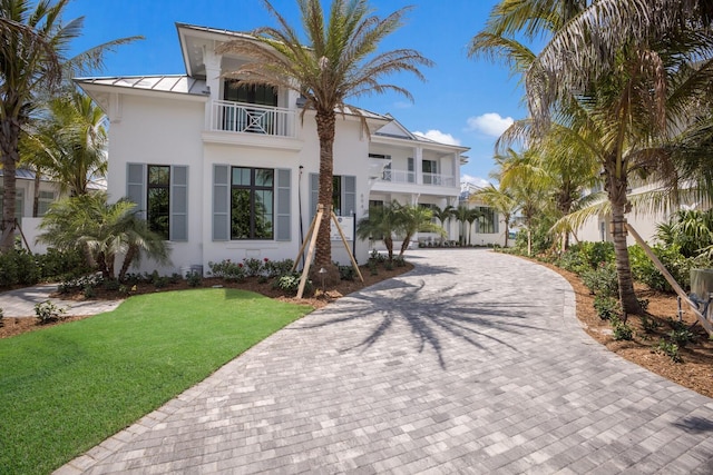 894 Hill Tide Ln, Boca Grande, FL 33921 - view of front of house featuring a balcony, a standing seam roof, decorative driveway, stucco siding, and a front lawn