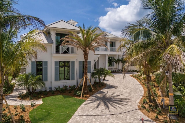 894 Hill Tide Ln, Boca Grande, FL 33921 - view of front of house featuring a balcony, curved driveway, a standing seam roof, and stucco siding