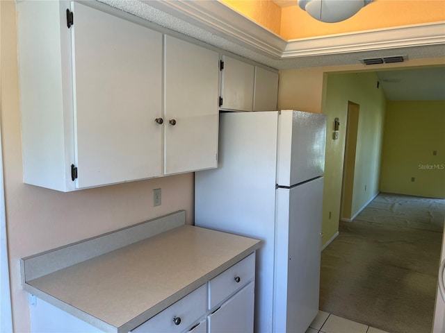 kitchen featuring light carpet, white refrigerator, and white cabinetry