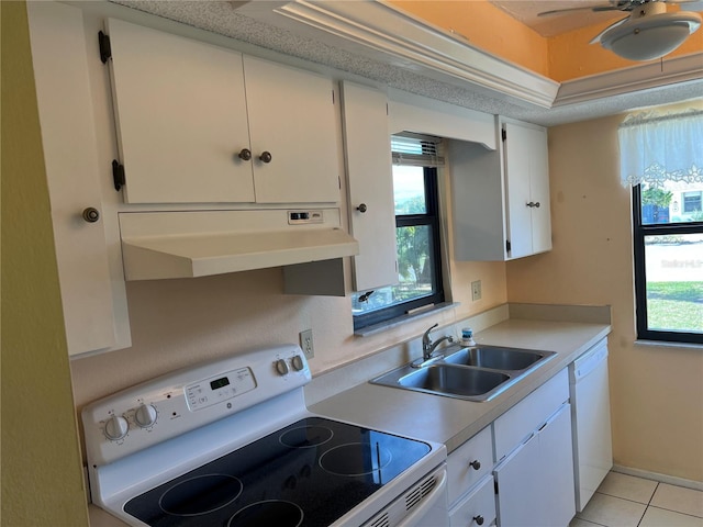 kitchen with stove, white cabinetry, light tile floors, and sink