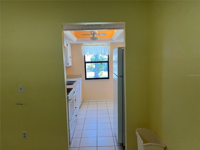 kitchen with light tile floors, white cabinets, stainless steel fridge, and ornamental molding