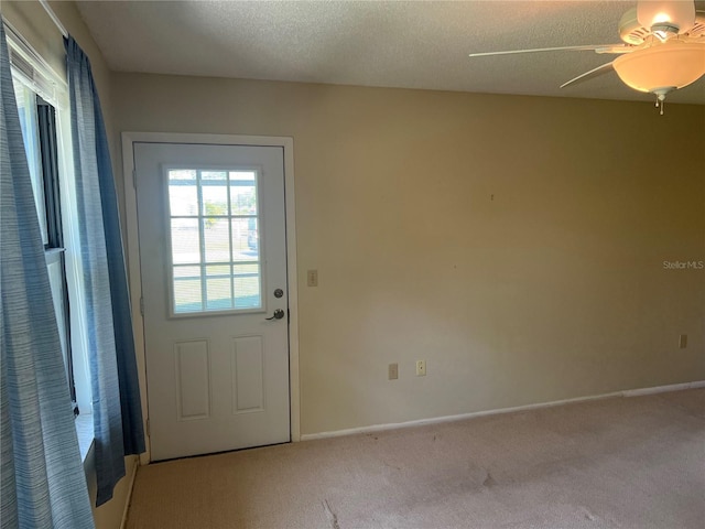 doorway with light carpet, a textured ceiling, and ceiling fan