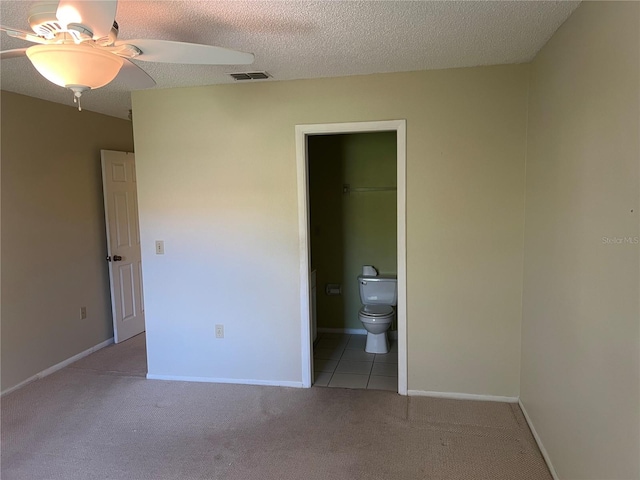 unfurnished bedroom with a closet, light carpet, a spacious closet, and ceiling fan