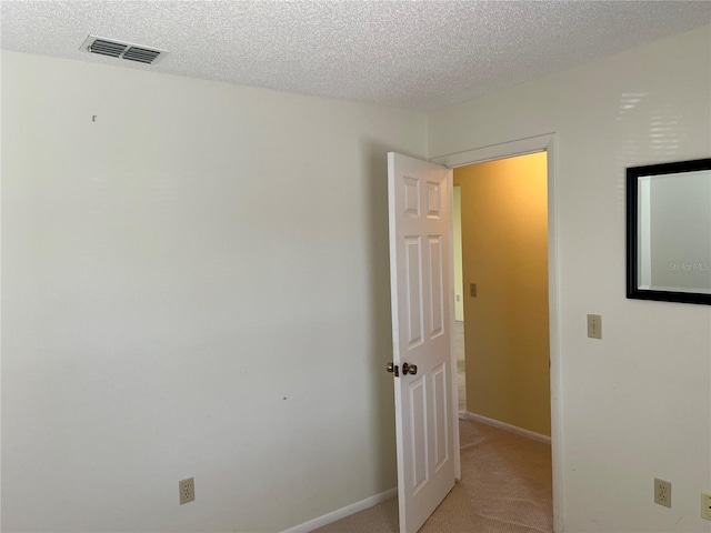 interior space with light carpet and a textured ceiling