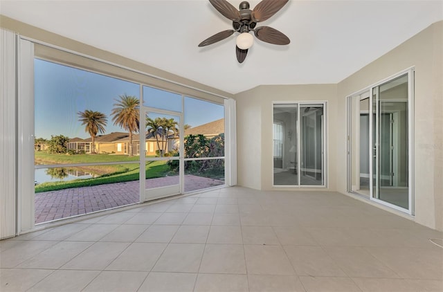 unfurnished sunroom featuring a water view and ceiling fan