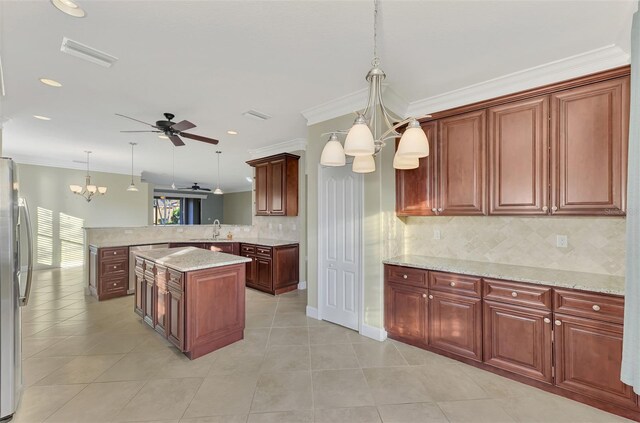 kitchen featuring hanging light fixtures, a peninsula, freestanding refrigerator, and a sink