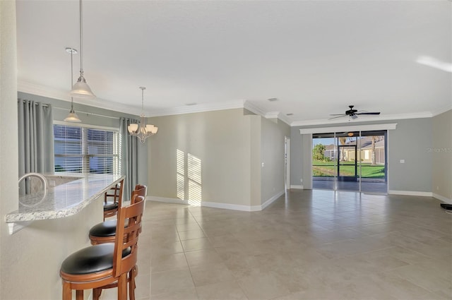 spare room with light tile patterned flooring, ceiling fan with notable chandelier, crown molding, and baseboards