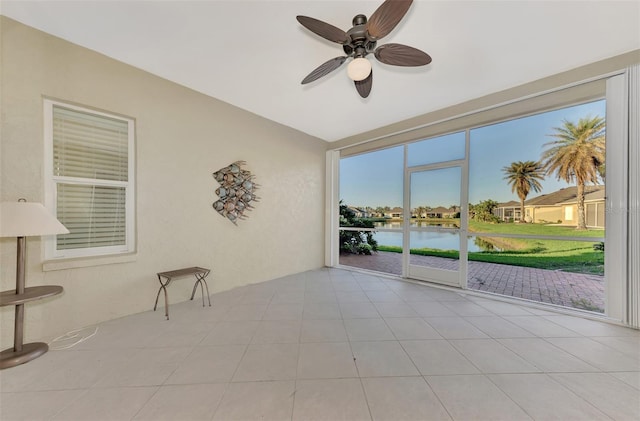 unfurnished sunroom featuring a water view and ceiling fan