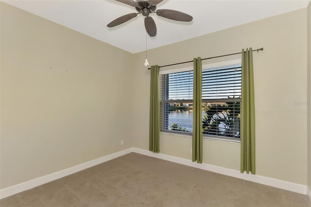 empty room featuring light colored carpet, a ceiling fan, and baseboards