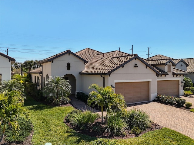 mediterranean / spanish home with a garage and a front lawn