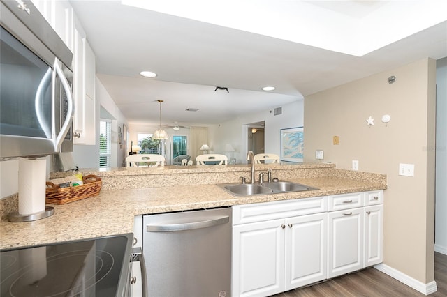 kitchen featuring kitchen peninsula, dark wood-type flooring, appliances with stainless steel finishes, and sink