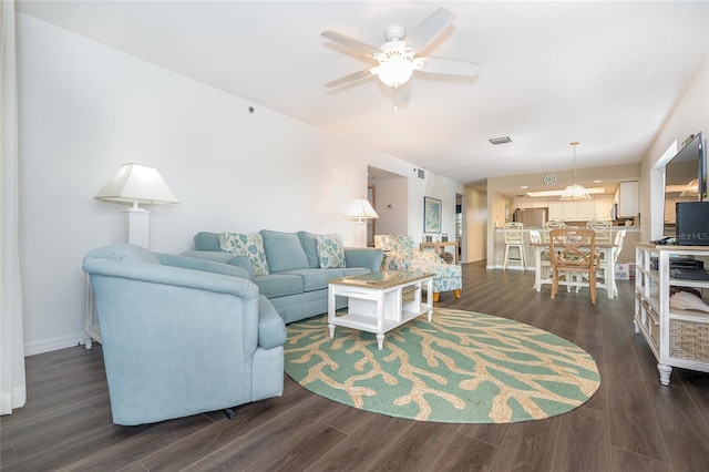 living room with ceiling fan with notable chandelier and dark hardwood / wood-style flooring