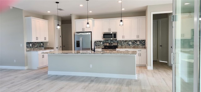 kitchen with pendant lighting, a center island with sink, white cabinetry, and stainless steel appliances