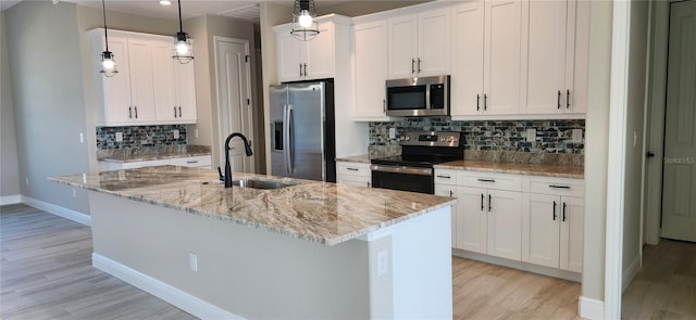 kitchen with a center island with sink, white cabinets, and stainless steel appliances