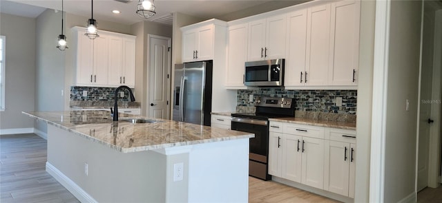 kitchen with sink, hanging light fixtures, an island with sink, white cabinets, and appliances with stainless steel finishes