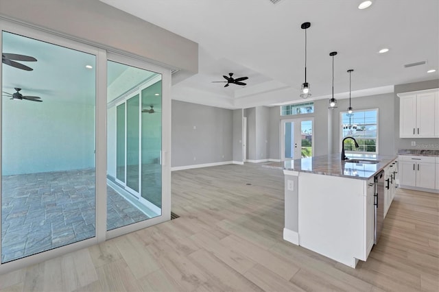 kitchen with french doors, sink, white cabinets, and a center island with sink