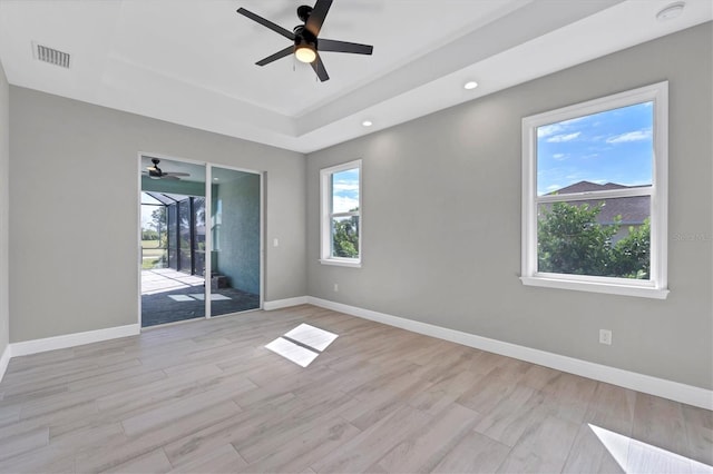 spare room featuring ceiling fan, light hardwood / wood-style floors, and a raised ceiling