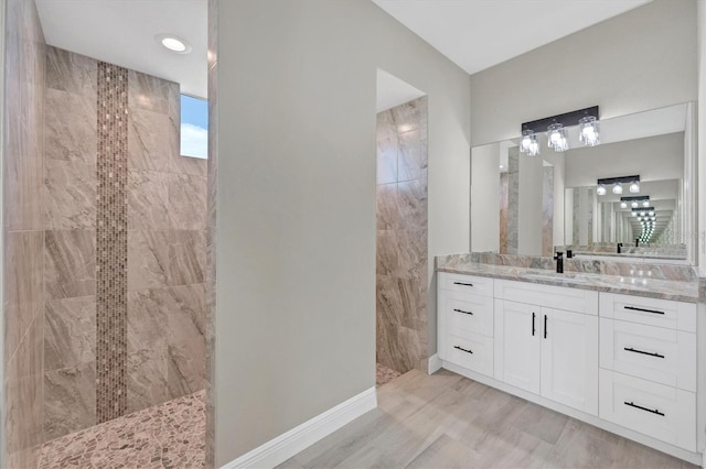 bathroom featuring vanity, wood-type flooring, and tiled shower