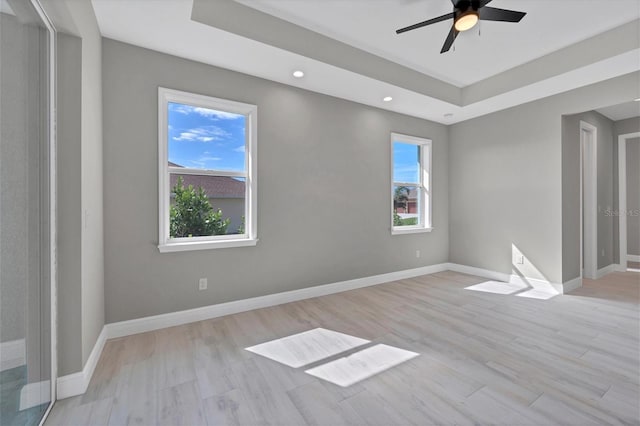 spare room featuring ceiling fan, light hardwood / wood-style floors, and a raised ceiling