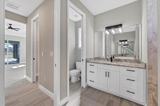 bathroom with ceiling fan, vanity, wood-type flooring, and toilet