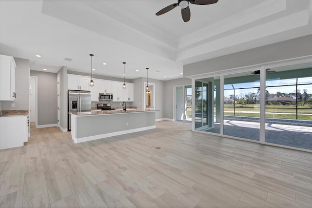 unfurnished living room with a raised ceiling, sink, ceiling fan, light wood-type flooring, and ornamental molding