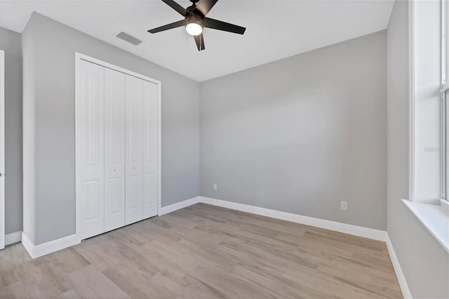 unfurnished bedroom featuring multiple windows, a closet, ceiling fan, and light hardwood / wood-style floors