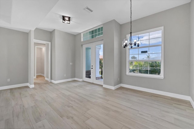 interior space featuring a chandelier, french doors, and light wood-type flooring