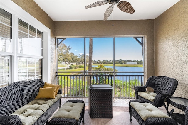 sunroom with plenty of natural light, ceiling fan, and a water view