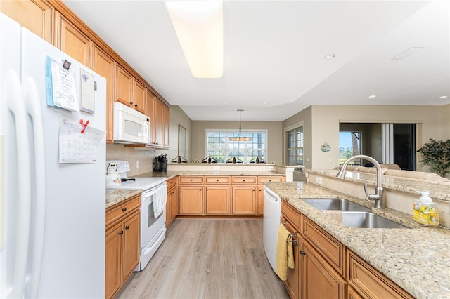 kitchen with white appliances, sink, light hardwood / wood-style flooring, light stone counters, and pendant lighting