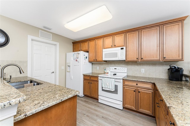 kitchen with white appliances, backsplash, sink, and light wood-type flooring