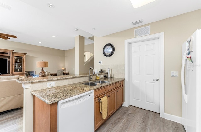 kitchen featuring light stone countertops, kitchen peninsula, ceiling fan, white appliances, and light wood-type flooring