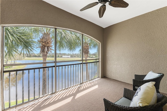 unfurnished sunroom featuring ceiling fan and a water view