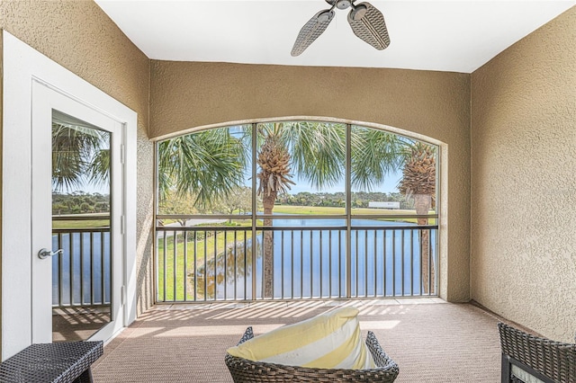 sunroom / solarium featuring ceiling fan and a water view