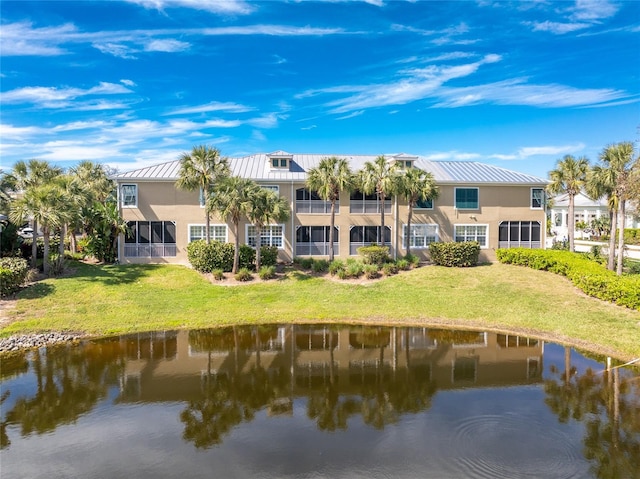 exterior space with a balcony, a lawn, and a water view