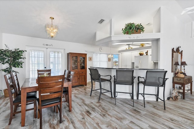 dining room featuring french doors, high vaulted ceiling, ceiling fan with notable chandelier, and light hardwood / wood-style flooring