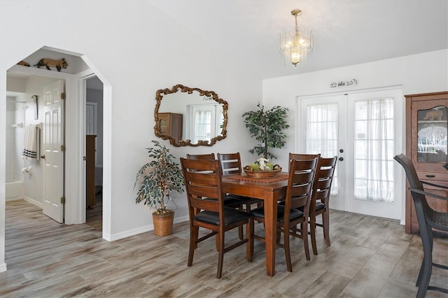 dining space featuring french doors, a notable chandelier, and light hardwood / wood-style flooring