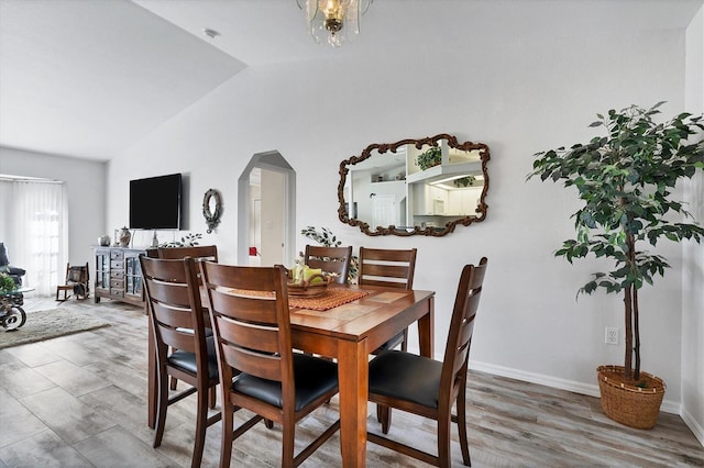 dining space with a chandelier, hardwood / wood-style floors, and high vaulted ceiling