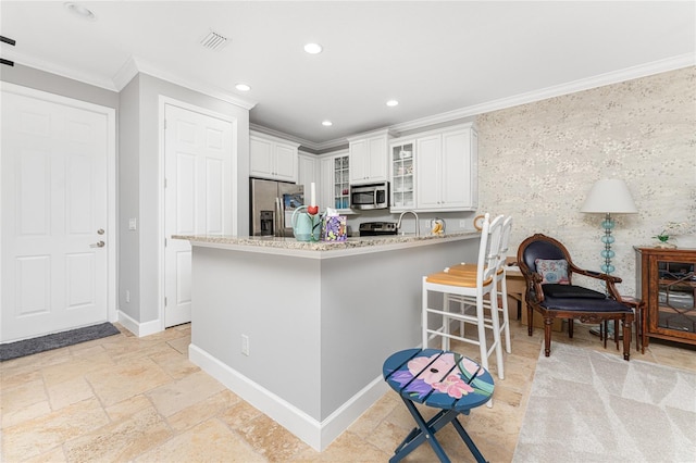 kitchen with light tile floors, crown molding, stainless steel appliances, light stone countertops, and white cabinetry