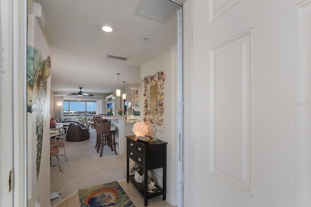 corridor featuring an inviting chandelier and light colored carpet