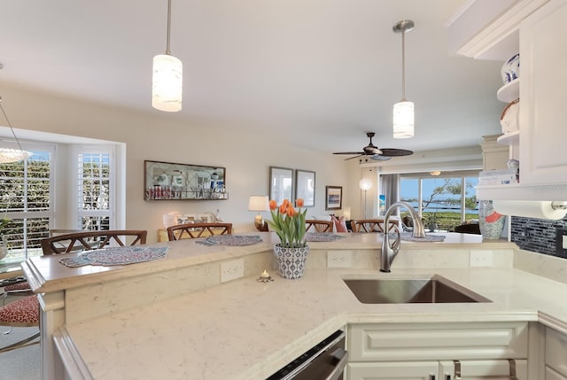 kitchen with pendant lighting, ceiling fan with notable chandelier, sink, and a wealth of natural light